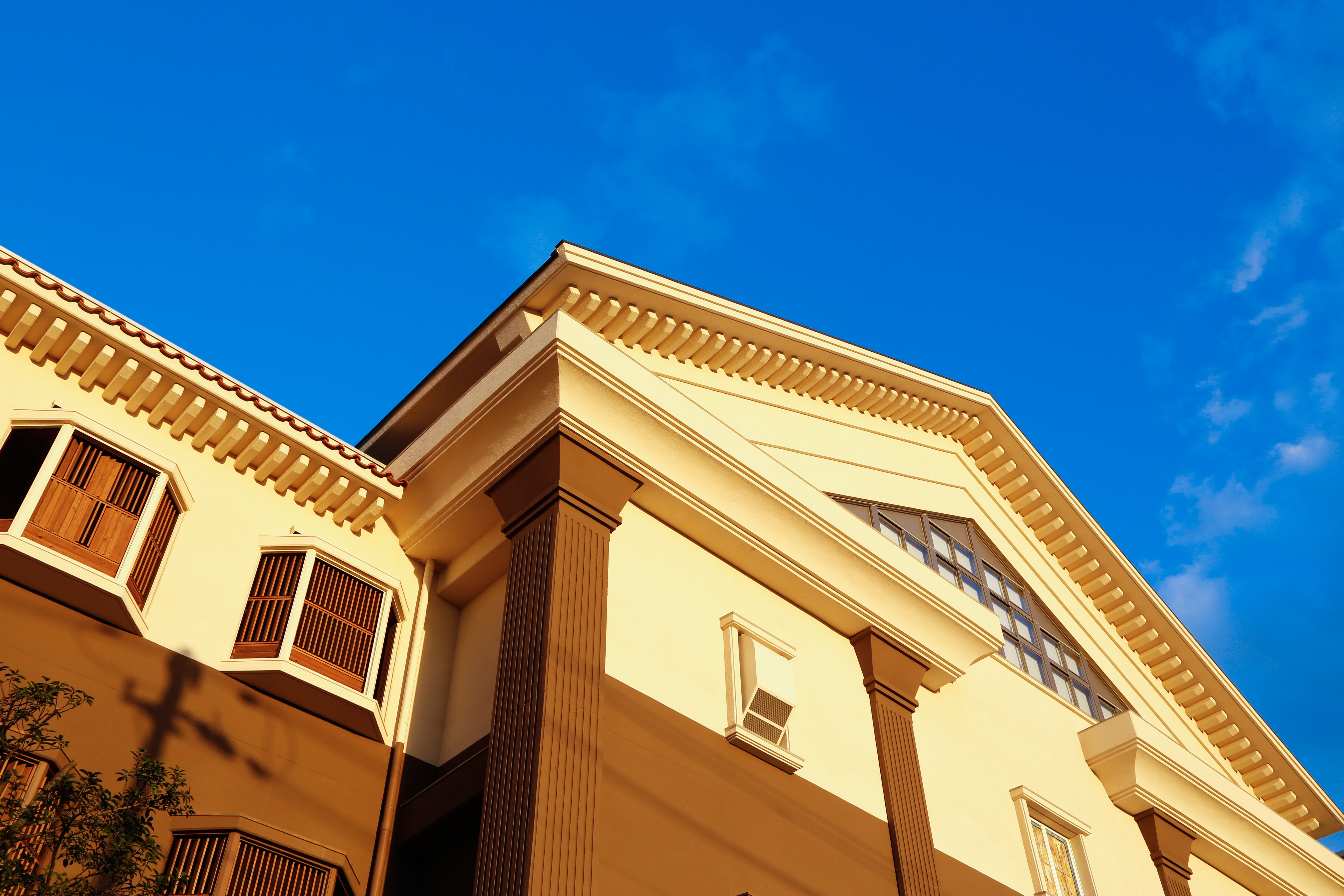 Classical facade of a Hotel New Awaji Group property looking up toward a clear blue sky, conveying architectural refinement and a sense of arrival