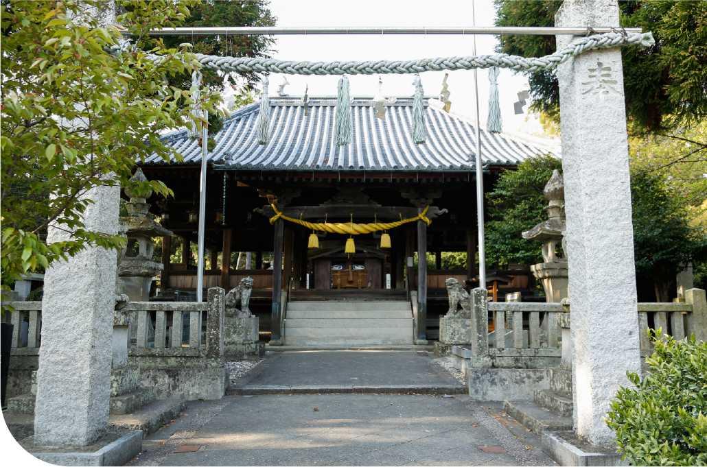 Stone torii gate entrance to an Awaji Island shrine draped with lanterns and framed by lush greenery, inviting quiet reflection and cultural connection