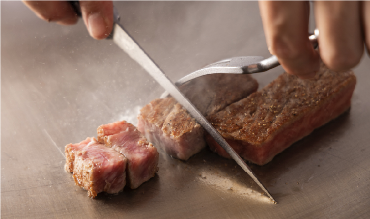 Chef slicing premium Kobe beef, showcasing a refined dining experience central to Kobe's global culinary reputation