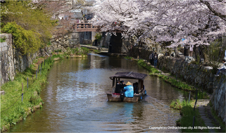 Traditional boat cruising through Omi Hachiman canal lined with historic buildings, offering a calm and cultural lakeside town experience