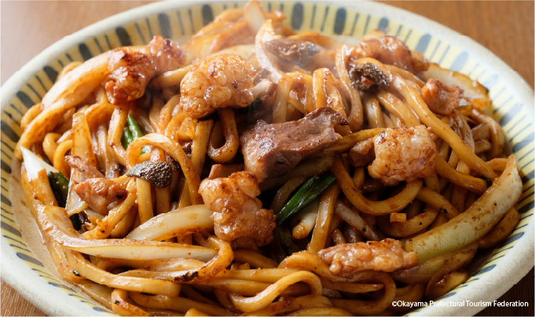 Plate of stir-fried udon noodles with meat and vegetables, showcasing a local comfort dish unique to the Tsuyama region