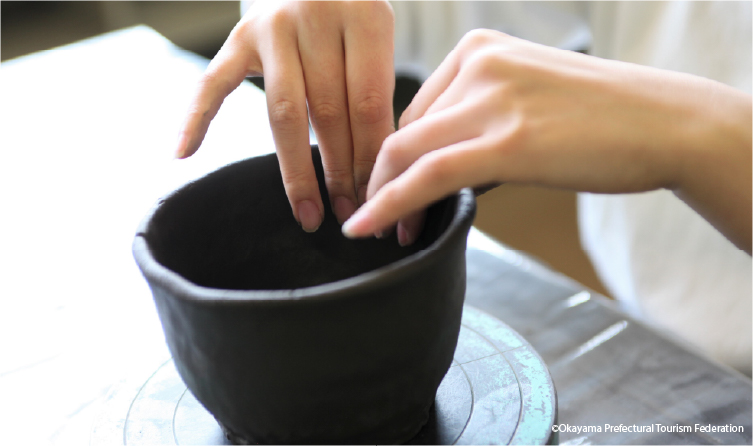 Hands shaping clay pottery in a Bizen workshop, offering a hands-on craft experience rooted in traditional Japanese ceramics
