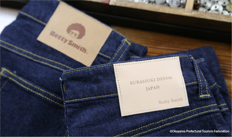 Hands customizing denim at a jeans workshop, offering a creative and personalized fashion experience in Okayama