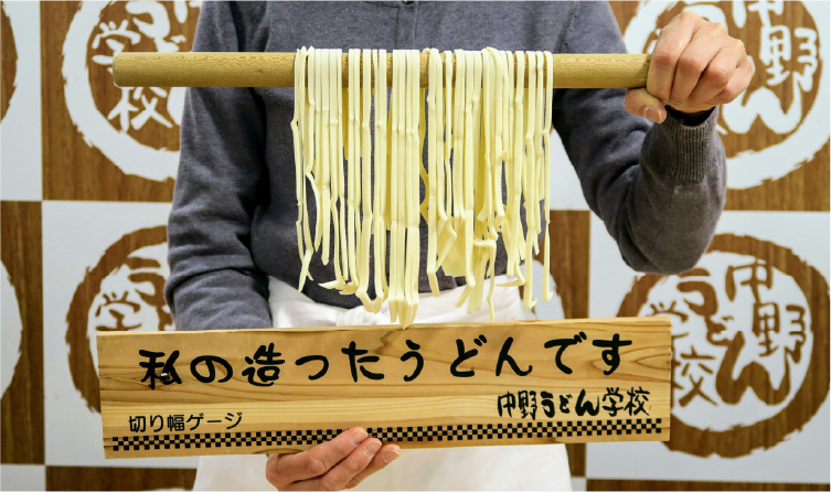 Hands holding freshly made udon noodles during a workshop, offering a fun and interactive local food experience in Shikoku