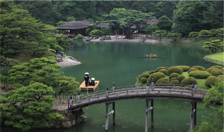 Traditional Japanese garden with pond and arched bridge in Takamatsu, offering a serene and meticulously landscaped walking experience