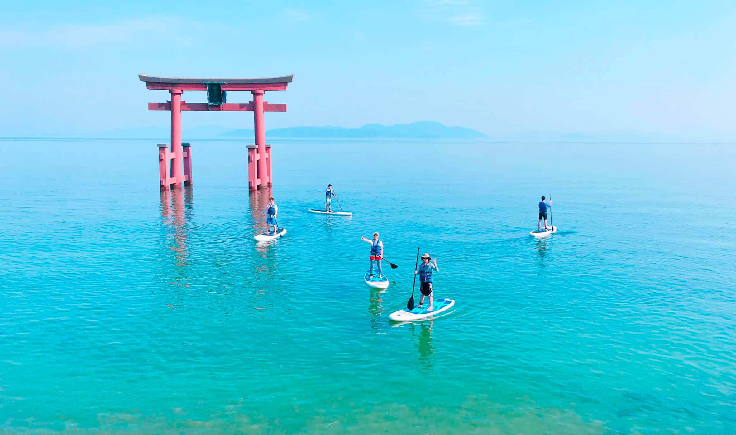 Paddleboarding near a torii gate in the ocean, scenic coastal activity in Japan