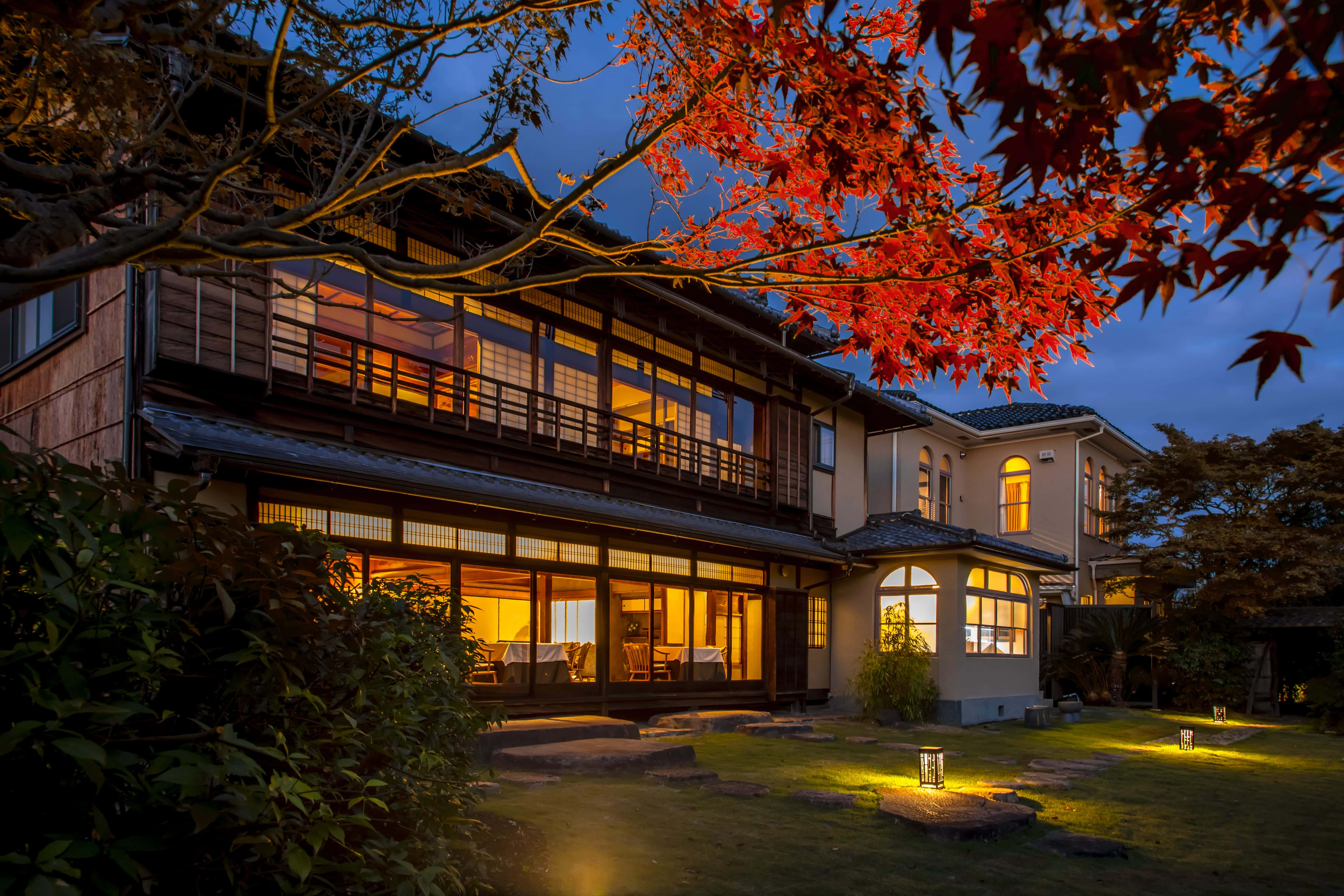Traditional Kyoto ryokan exterior at night with autumn foliage and illuminated garden, Kyoto Japan