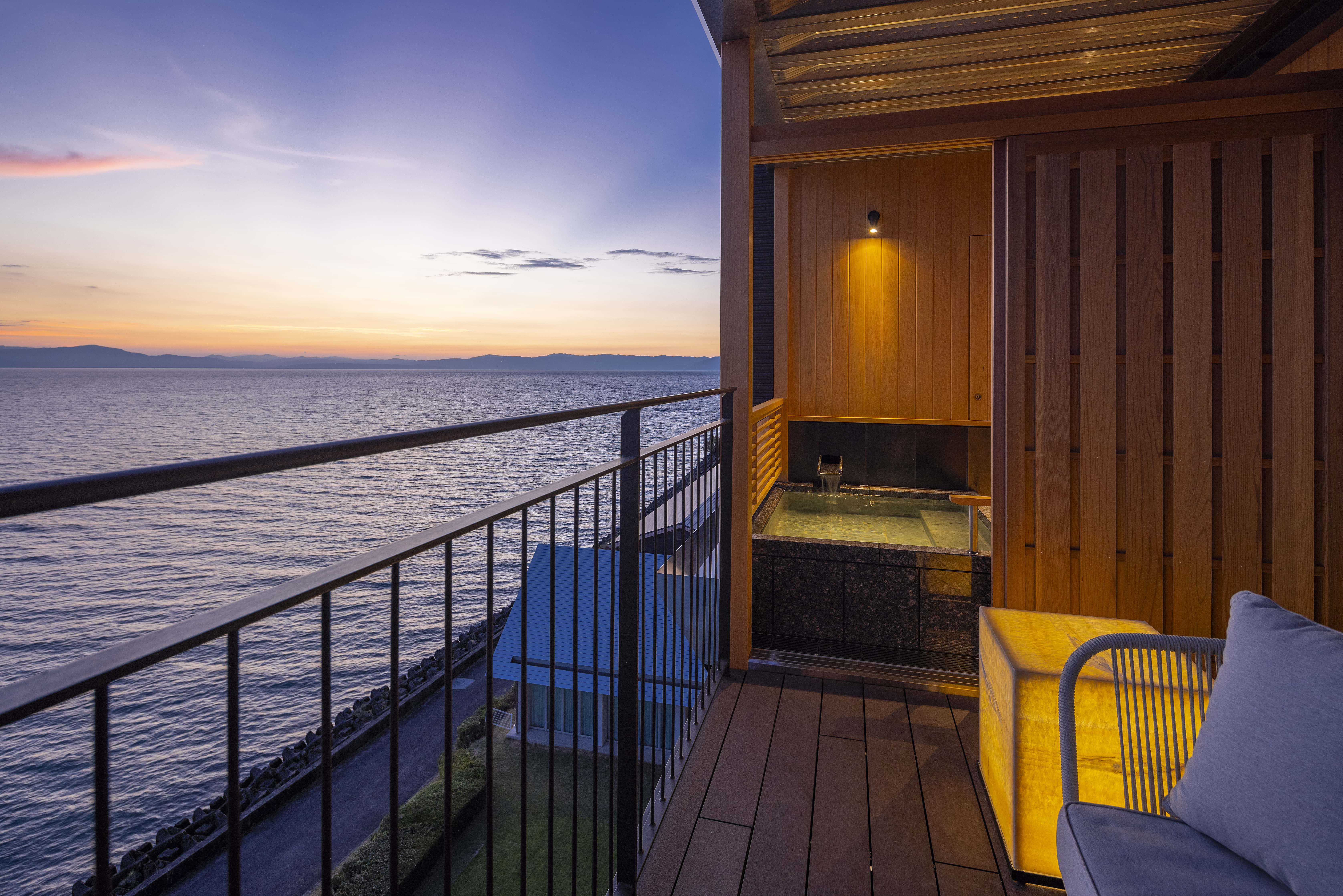 Private balcony with open-air bath overlooking the ocean at sunset, guest room on Awaji Island Japan