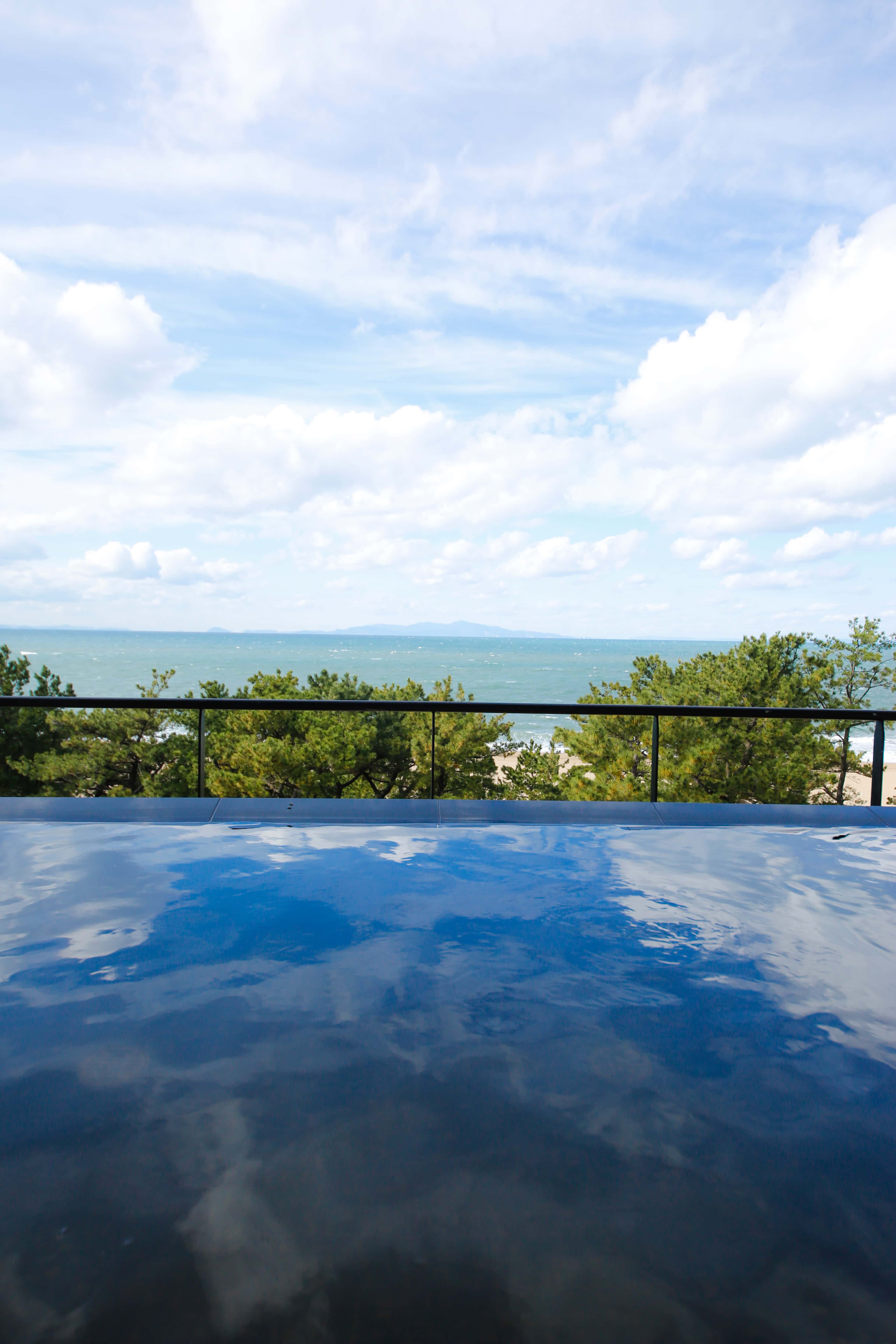 Open-air hot spring bath with panoramic ocean view under blue sky, Awaji Island onsen experience