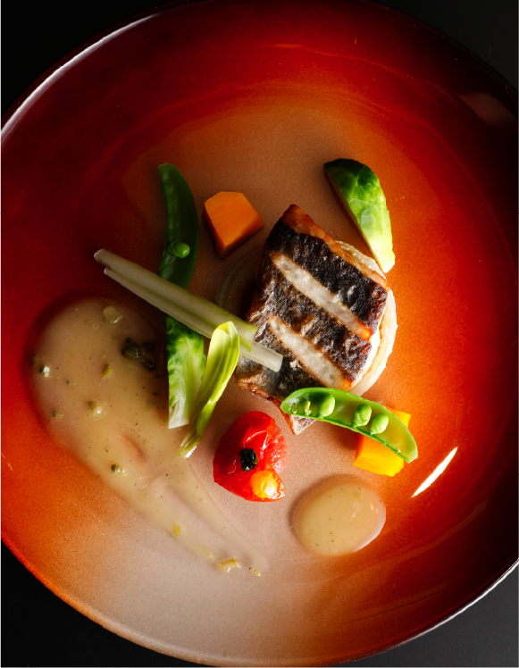 Seasonal plated fish dish with fresh vegetables and delicate sauce, showcasing refined kaiseki-style dining