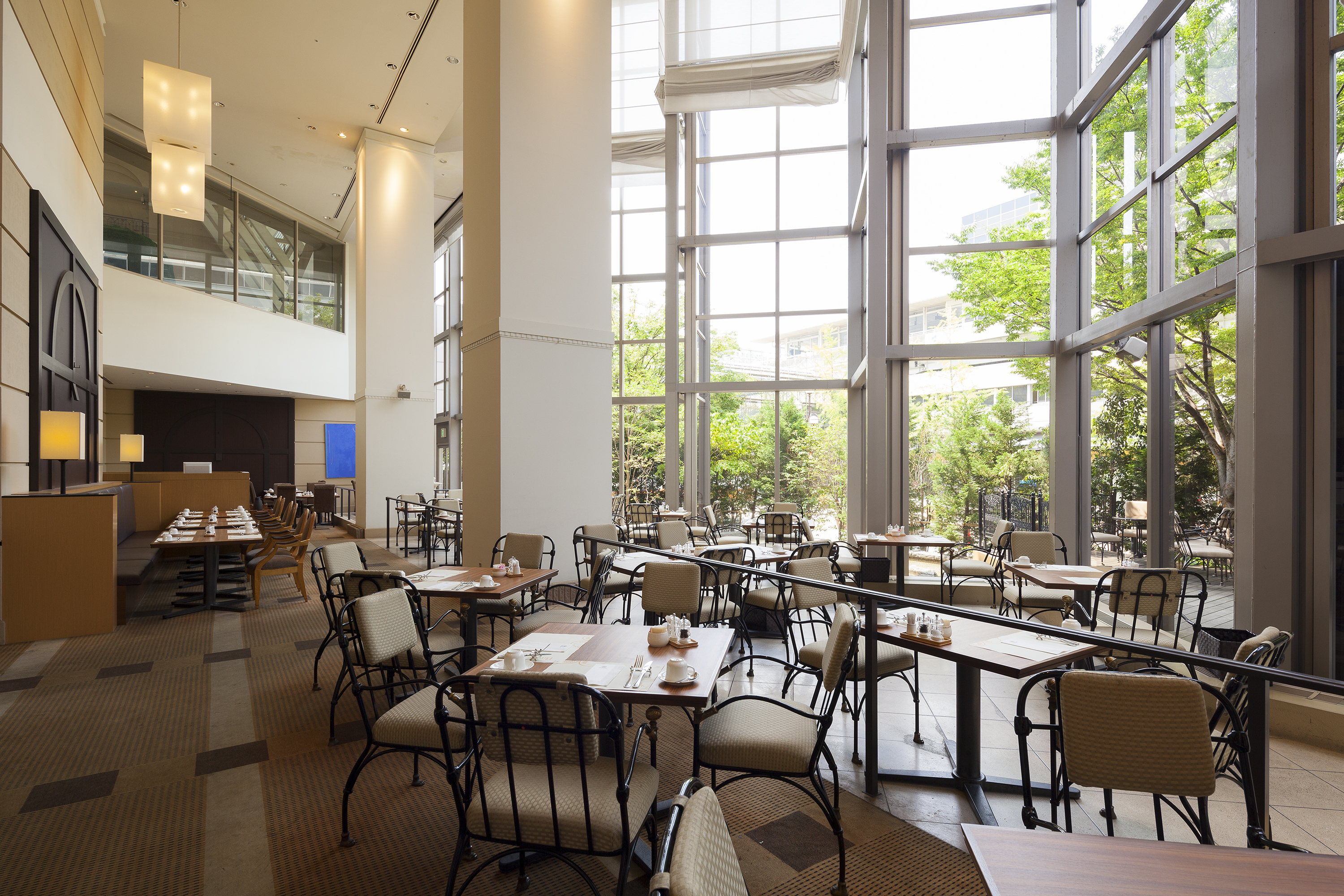 Bright cafe dining room with large windows and natural light at Kobe Bay Sheraton, part of Hotel New Awaji Group, offering a relaxed and luminous setting for breakfast or afternoon dining