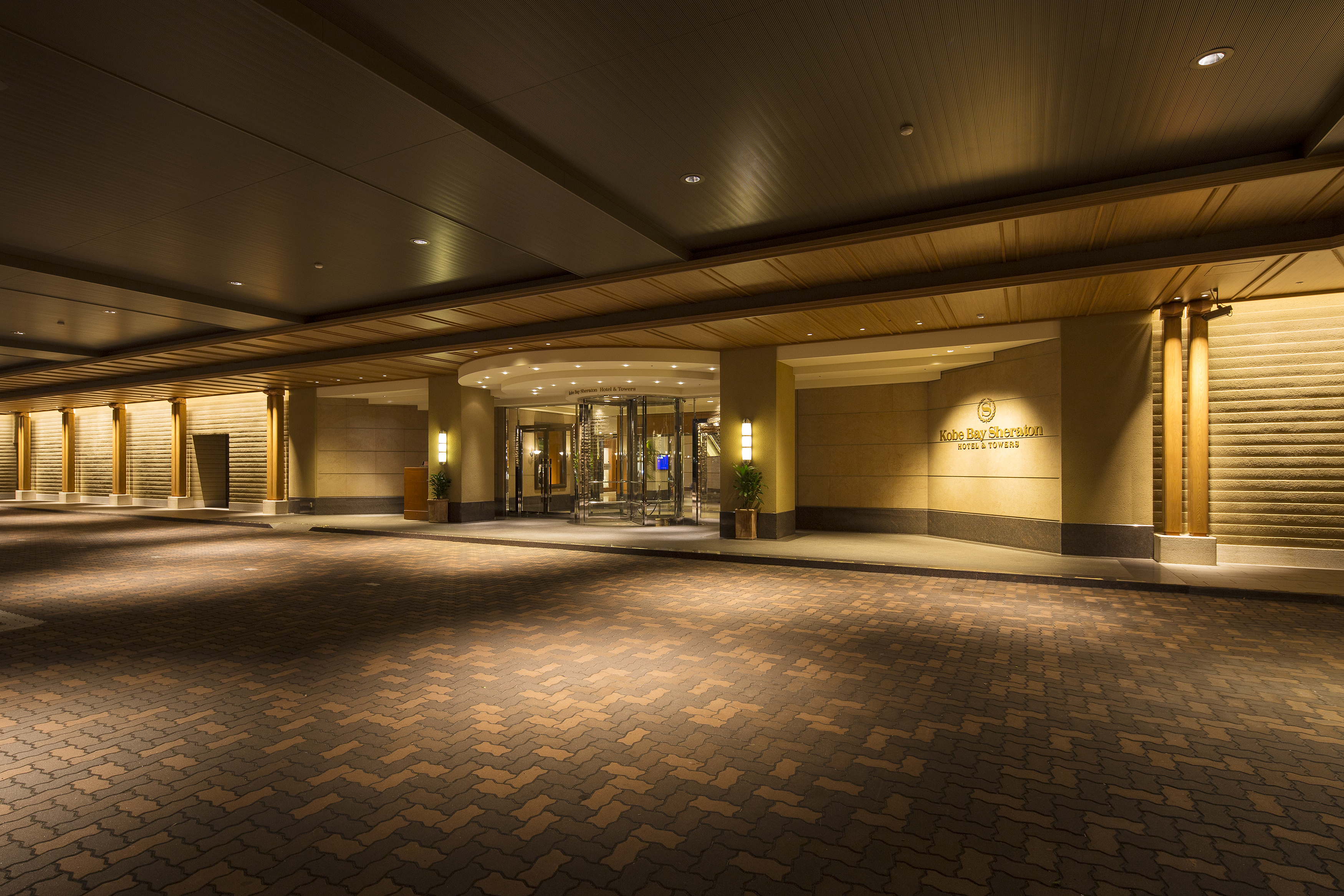 Grand hotel lobby entrance with high ceilings and warm polished floors at Kobe Bay Sheraton, part of Hotel New Awaji Group, setting a tone of confident and understated luxury on arrival