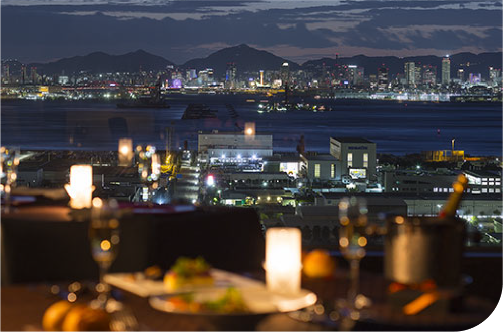 Candlelit table overlooking Kobe's glittering city lights from above, where dining becomes an experience of atmosphere, perspective, and quiet urban sophistication