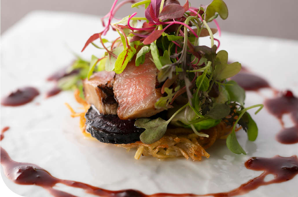 Elegantly plated Kobe Wagyu with microgreens and sauce reduction on white porcelain, a signature expression of the precision and refinement that defines Kobe's culinary identity