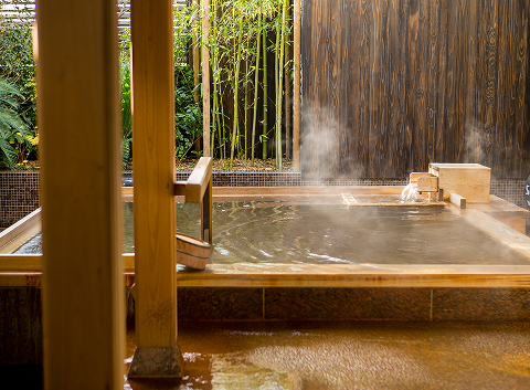Indoor onsen with warm ambient light and bamboo garden view, offering a restorative escape from the energy of Kobe's city and harbor