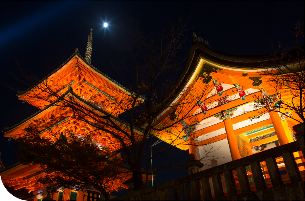 Multi-tiered Kyoto pagoda dramatically illuminated in gold against a dark night sky, revealing the city's timeless beauty after dark