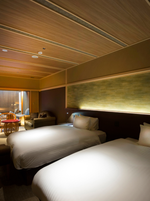 Modern twin guest room with warm wood ceiling panels and soft ambient lighting, combining contemporary comfort with understated Kyoto elegance