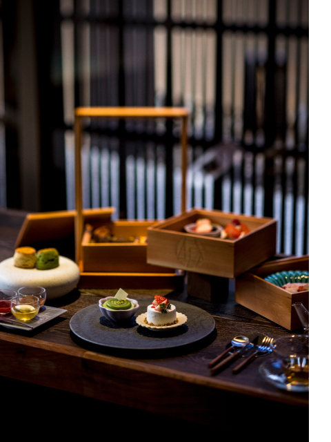 Private in-room onsen at Hotel New Awaji Group Kyoto with a dark wood tray of seasonal dishes beside steaming bath water, blending dining and wellness into a single intimate experience