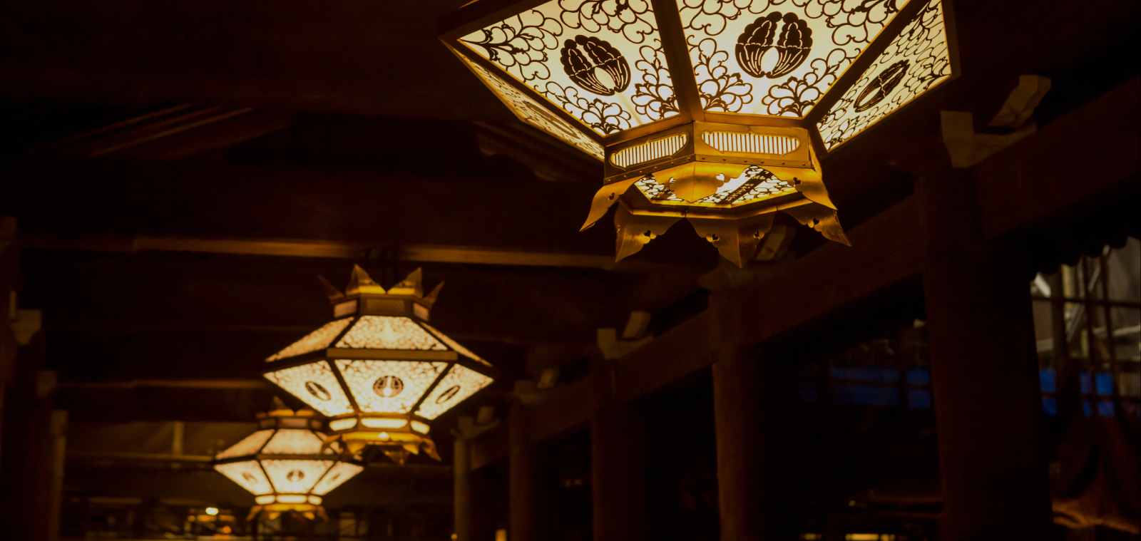 Glowing traditional lanterns hanging inside a Kyoto shrine, evoking centuries of ritual and cultural depth