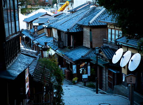 Narrow stone-paved alley lined with traditional machiya townhouses in Kyoto, capturing the city's layered history and quiet character