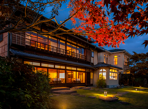 Hotel New Awaji Group Kyoto property warmly lit at dusk amid autumn foliage, offering a refined base for exploring the city's heritage