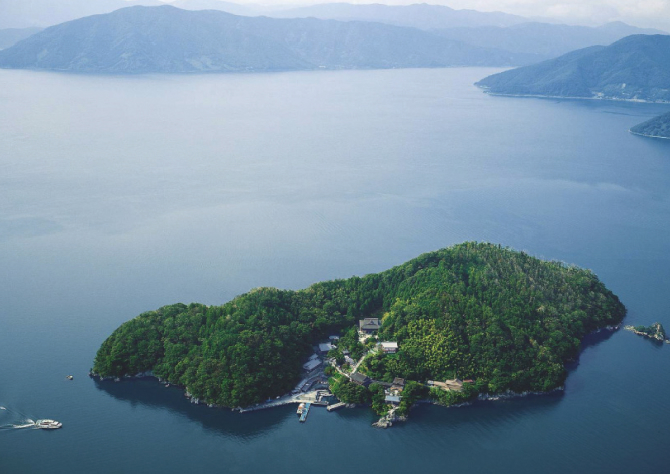 Small forested island rising from the calm surface of Lake Biwa, a sacred natural landmark at the heart of the region's spiritual identity