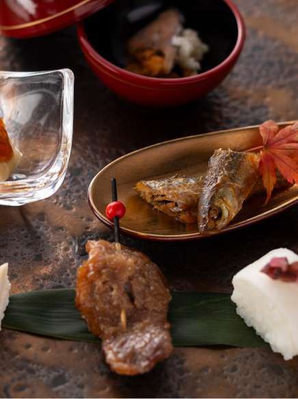 Seasonal kaiseki dishes presented in lacquered and glass vessels with autumn garnish, reflecting the refined dining experience at Hotel New Awaji Group's Lake Biwa property