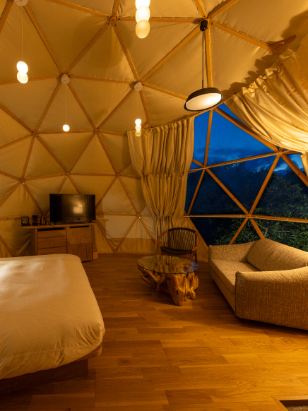 Warm interior of a geodesic dome accommodation at Hotel New Awaji Group, offering an intimate and distinctive lakeside retreat experience