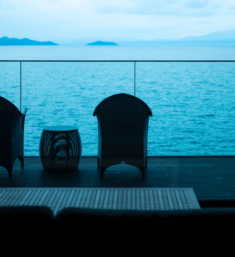 Private guest balcony with wicker armchairs at Hotel New Awaji Biwa Lake in Hikone, Shiga, Japan, overlooking the calm waters of Lake Biwa at dusk