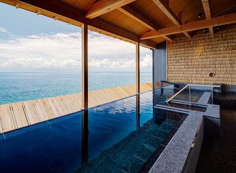 Open-air natural spring onsen at Hotel New Awaji Group overlooking Lake Biwa, blending indoor and outdoor bathing in a serene lakeside setting.