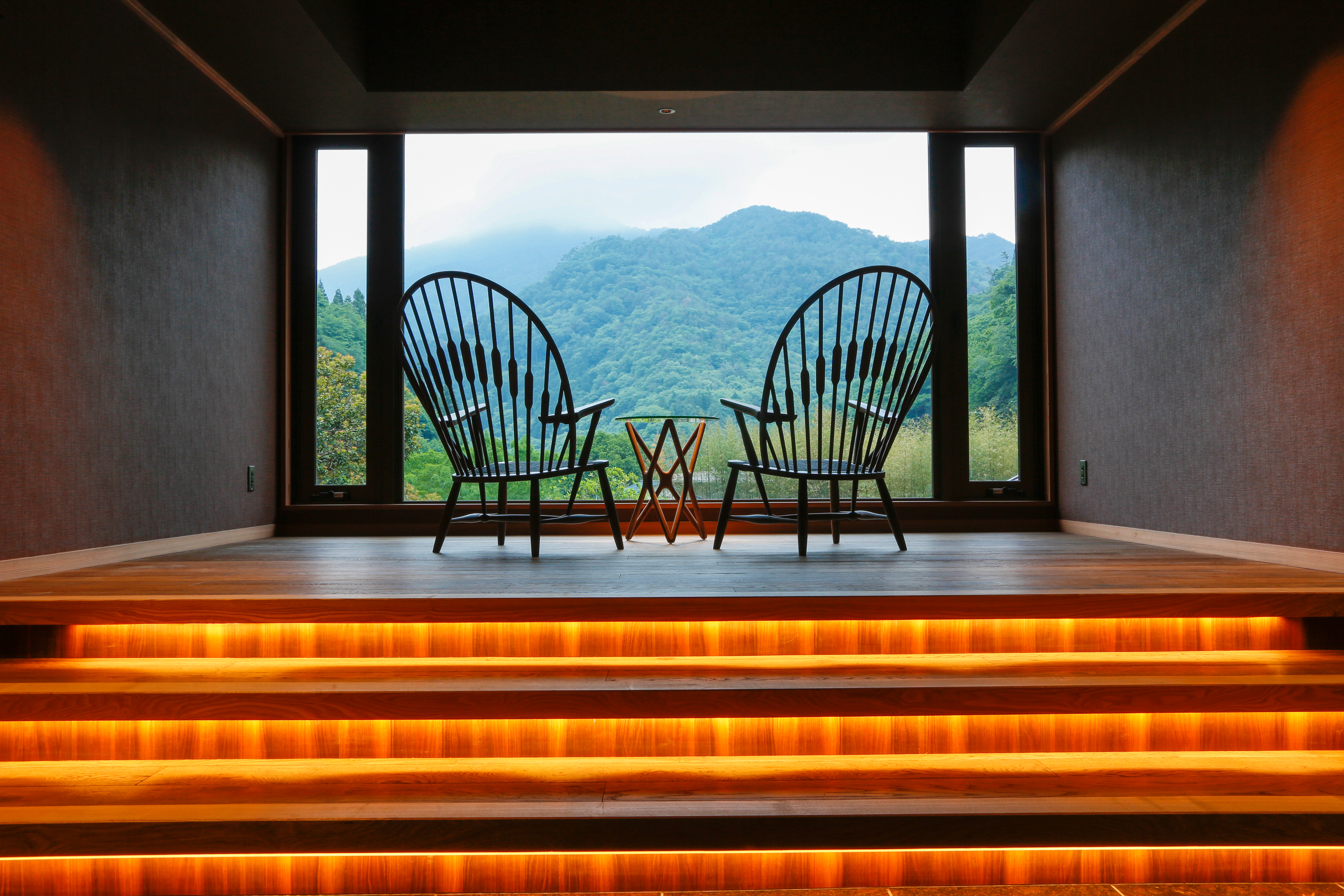 Open veranda with two chairs overlooking a panoramic green mountain landscape, an invitation to pause and take in the natural stillness of the region