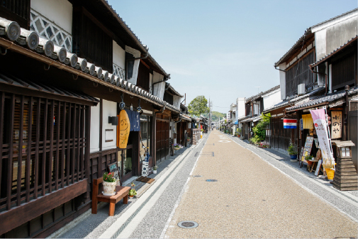 Quiet traditional merchant street in Okayama with historic shopfronts receding into the distance, where everyday life and enduring architecture exist in easy harmony