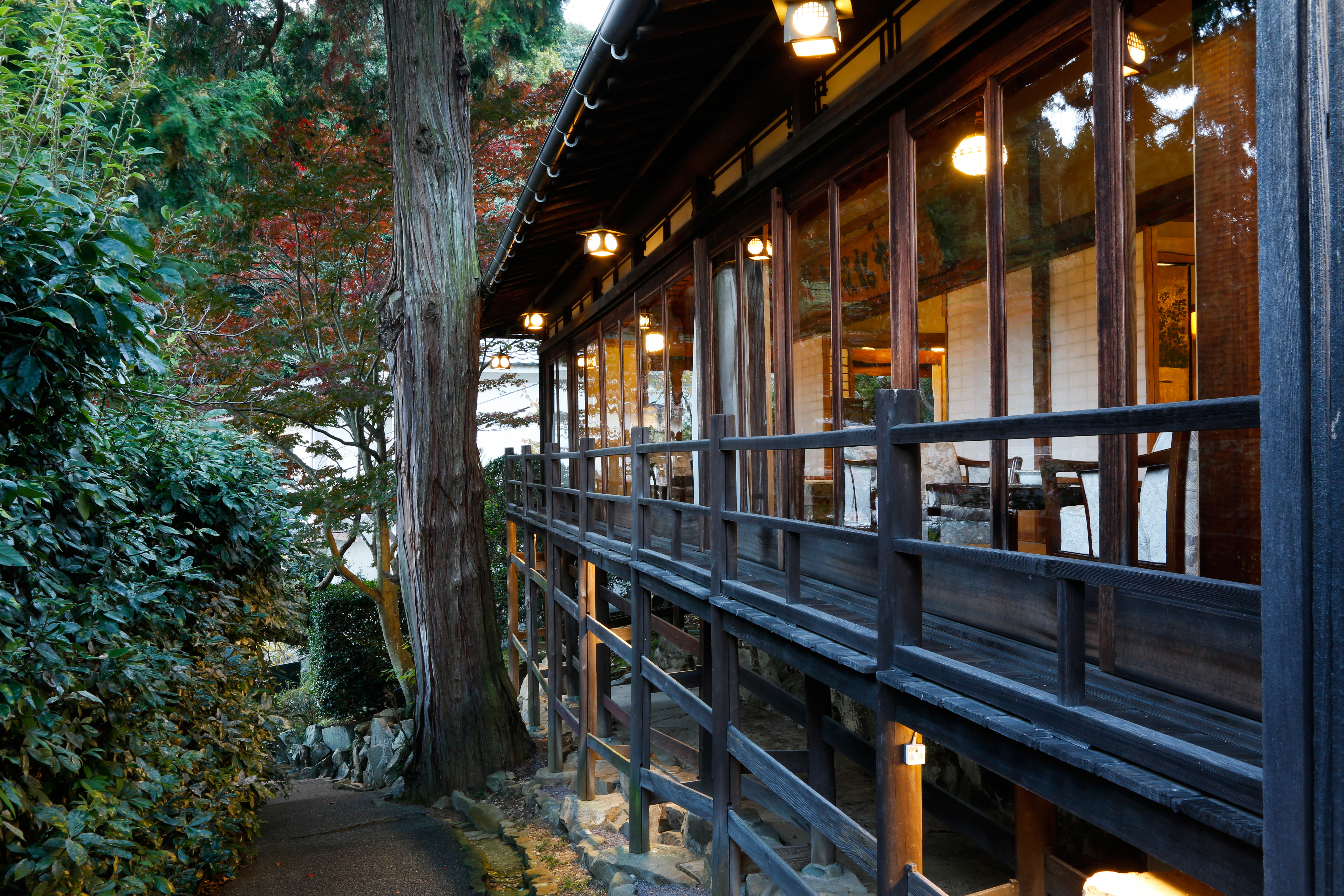 Traditional Japanese inn exterior with wooden verandas, stone lanterns, and manicured pine trees, embodying the quiet craftsmanship of a Shikoku ryokan stay