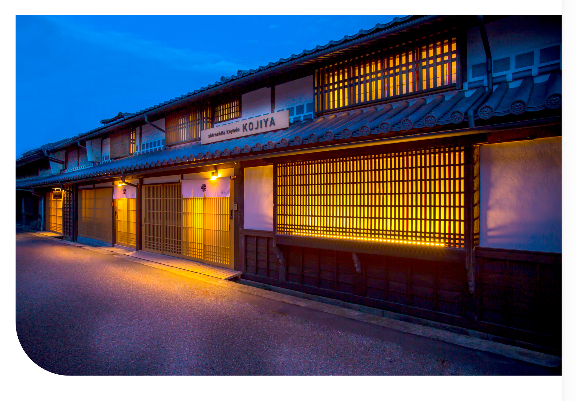Warmly lit traditional machiya streetscape in Okayama at dusk, where glowing shopfronts and centuries-old architecture create an atmosphere of enduring authenticity
