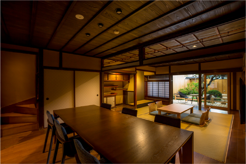 KOJITEA House A at Hotel Yuraku Kyo-omishima, a dark timber machiya-style room with low seating and garden screens, deeply rooted in the architectural heritage of the region