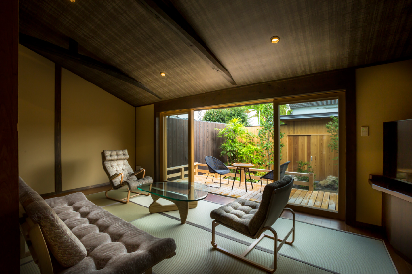 KOJITEA House B at Hotel Yuraku Kyo-omishima, an open-plan traditional room with warm wood tones and full-width garden screens, where indoor and outdoor living quietly merge