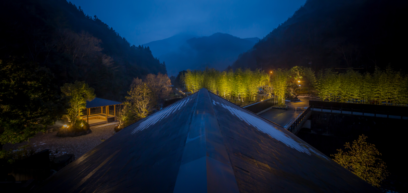 Illuminated garden path stretching toward misty mountains at twilight in Shikoku, evoking a sense of quiet discovery and spiritual depth