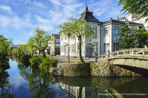 Historic white building reflected in a still moat in Okayama, where centuries of craftsmanship and regional identity remain alive